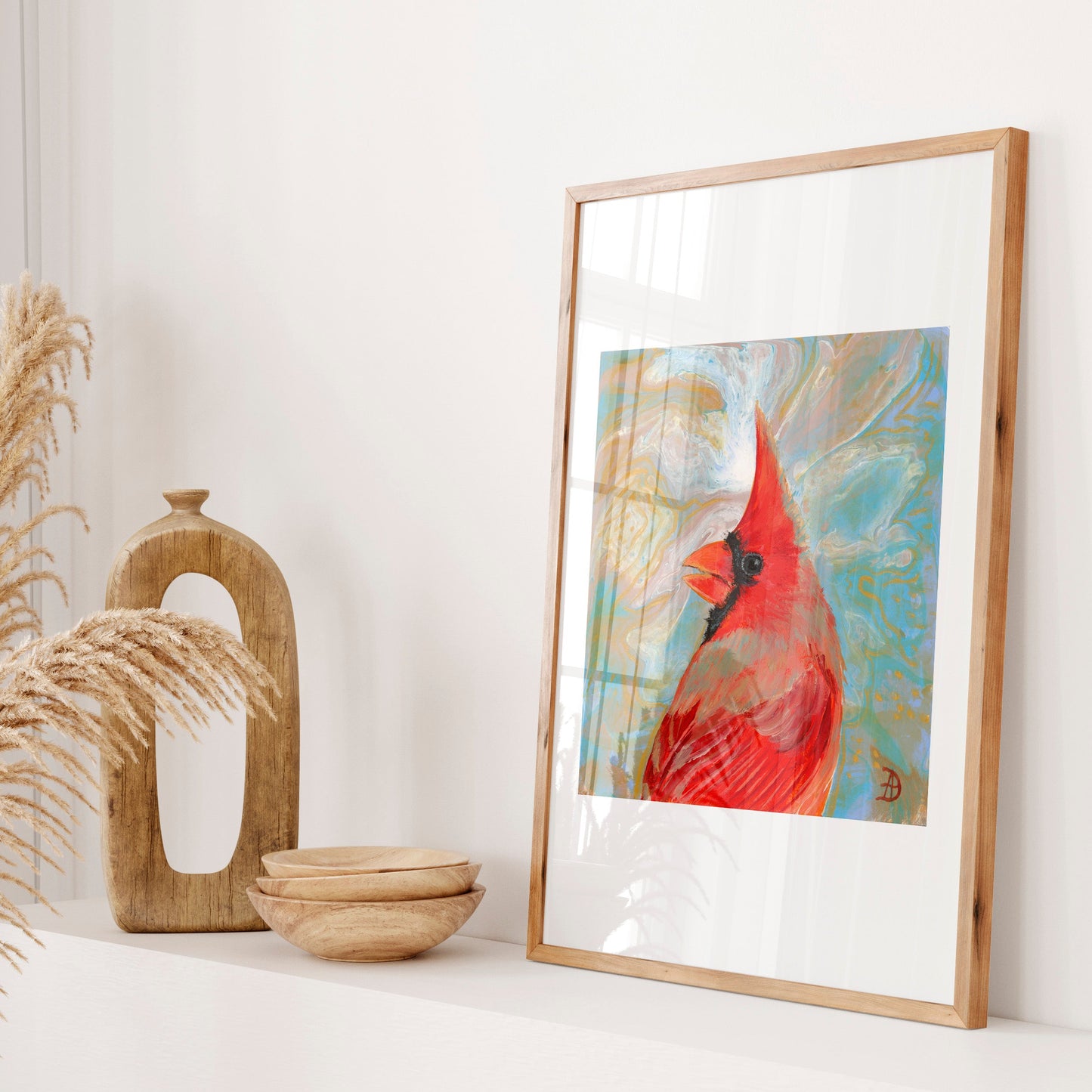 Framed artwork of a red cardinal bird on a white surface with decorative elements.