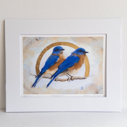Framed artwork of two blue birds on a branch with a circular design in the background.