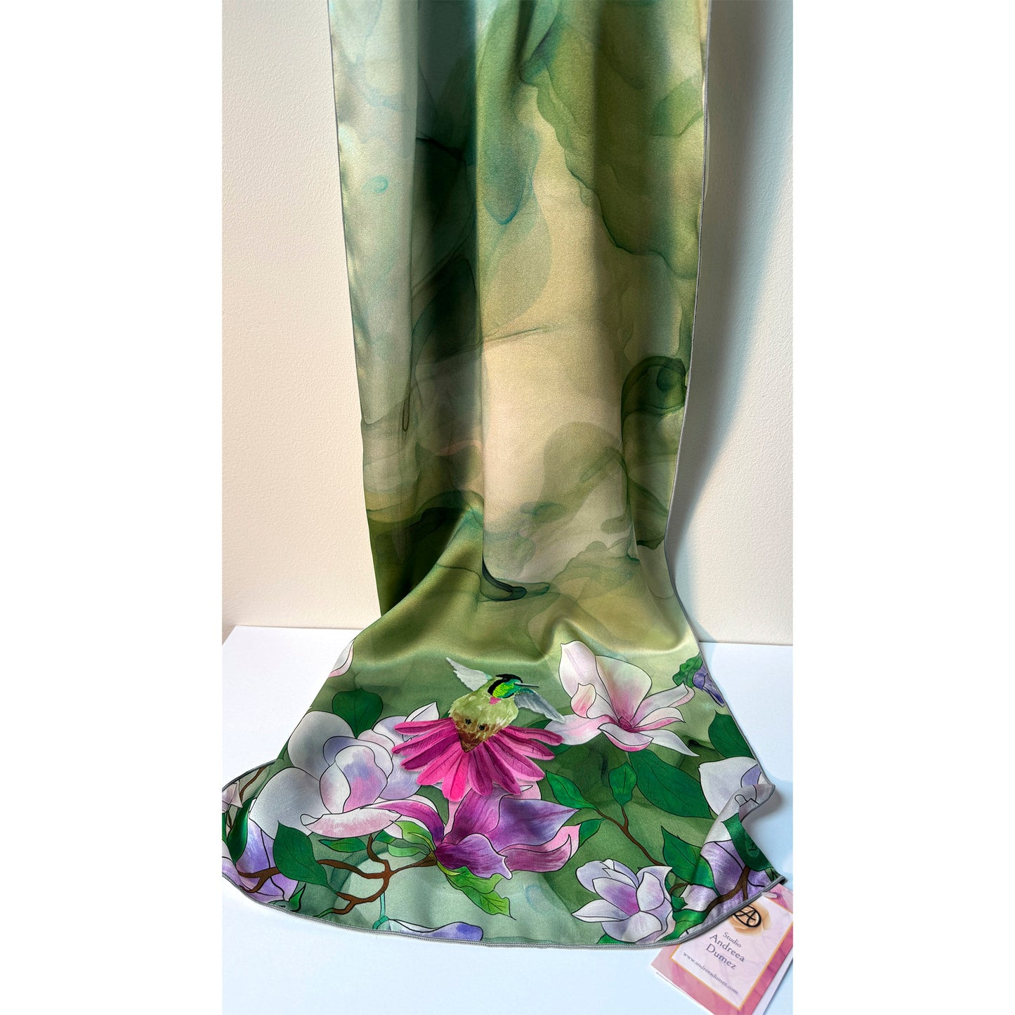 Floral patterned silk charmeuse scarf with pink and purple flowers and a hummingbird on a green background. Unique silk scarf suitable for client appreciation gifts and luxury corporate gifts. 