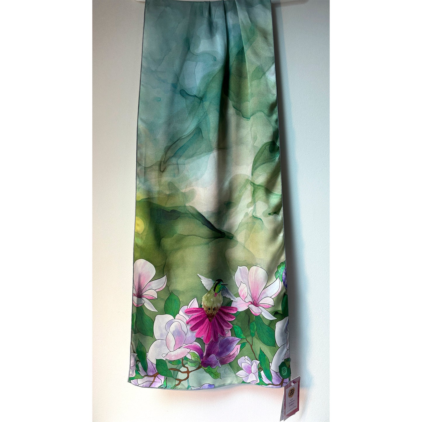 Floral patterned silk charmeuse scarf with pink and purple flowers and a hummingbird on a green background. Unique silk scarf suitable for client appreciation gifts and luxury corporate gifts. 
