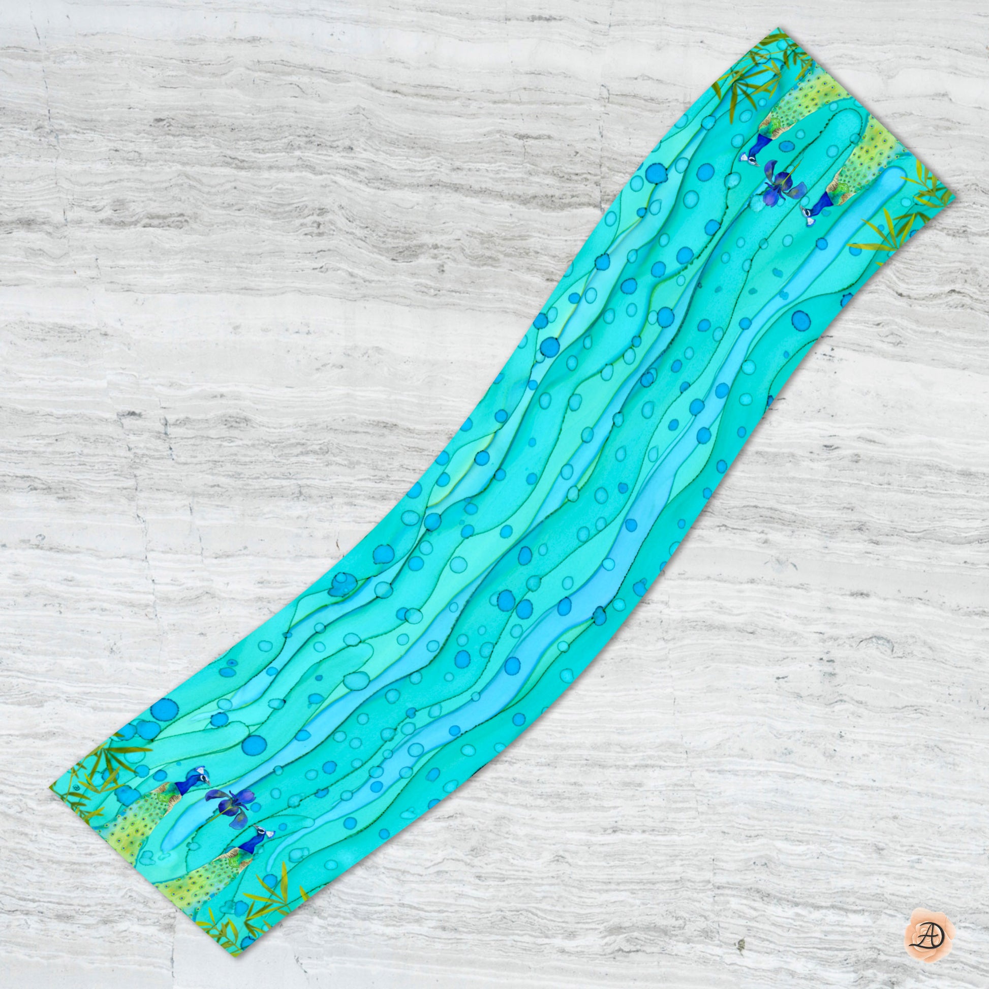 Teal silk scarf with wave pattern and peacocks on a light wooden surface. Unique silk scarf suitable for client appreciation gifts and luxury corporate gifts. 