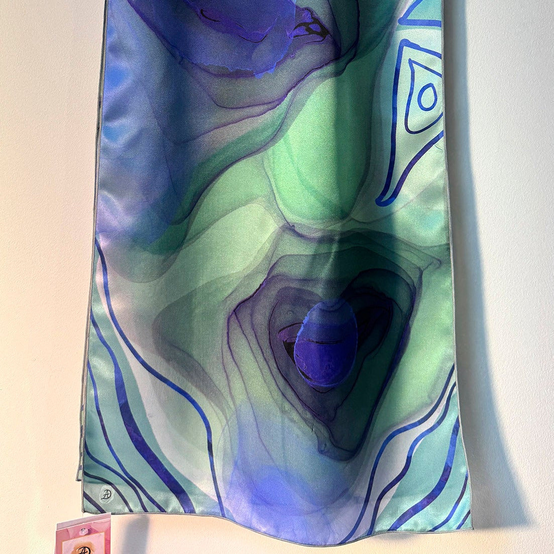 Colorful scarf with abstract blue and teal design on a white background
