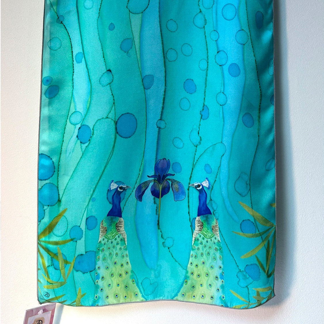 Teal scarf with peacock design on a white background