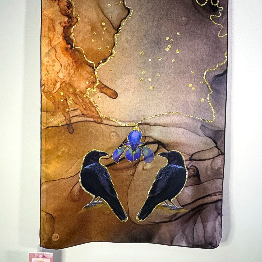 Silk scarf printed with an artistic depiction of two crows and a blue iris flower on a textured background with a white background