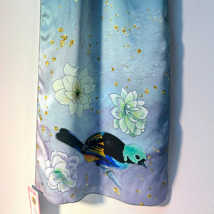 Blue silk scarf with floral and tanager bird design on a white background
