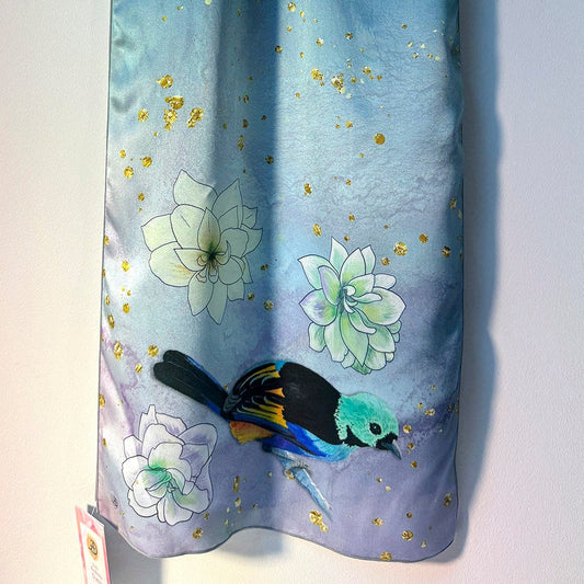 Blue silk scarf with floral and tanager bird design on a white background