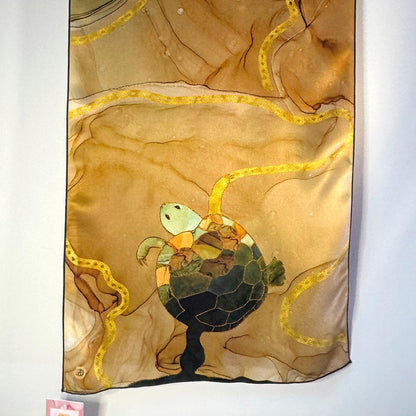 Decorative silk scarf with turtle design on a beige and green abstract background
