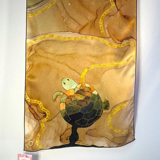 Decorative silk scarf with turtle design on a beige and green abstract background
