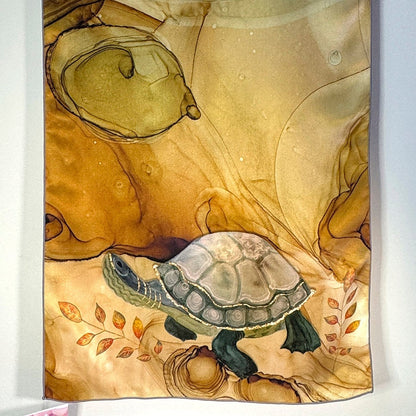 Decorative silk scarf fabric with a turtle design on a brown and tan background