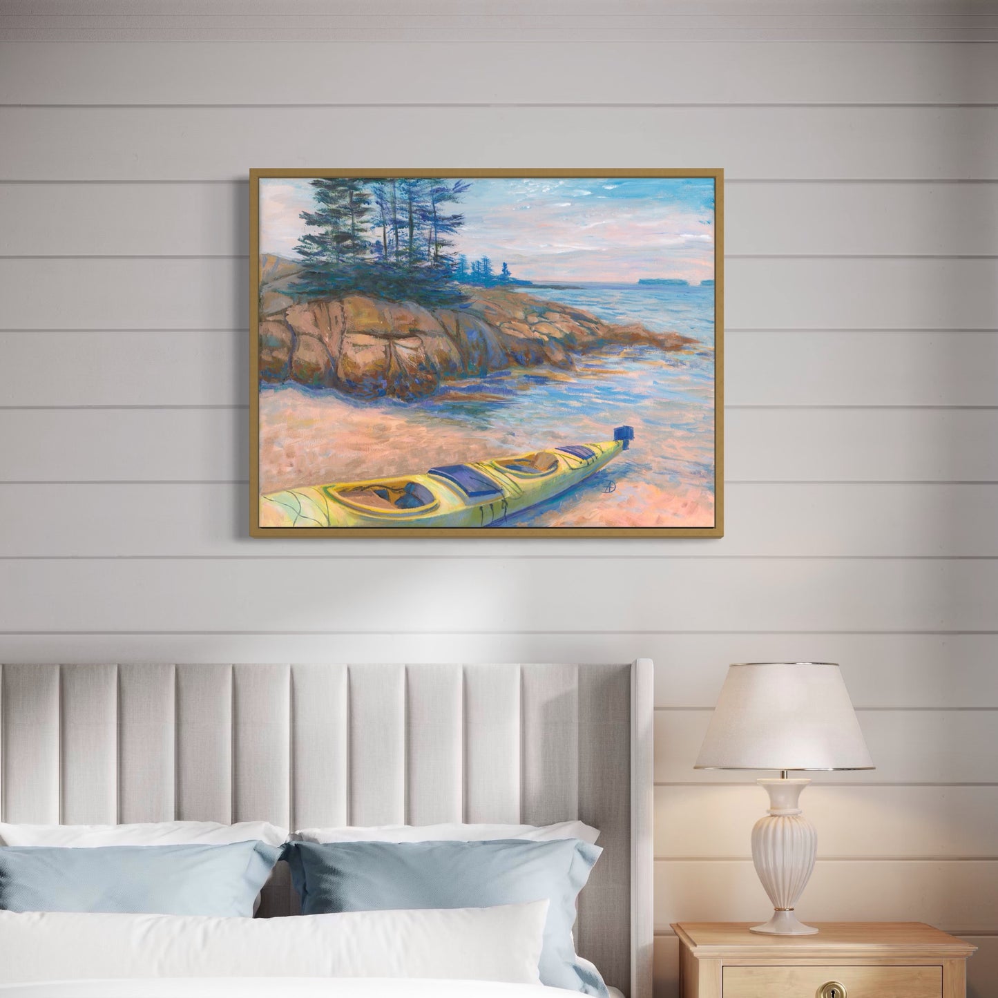Bedroom interior with an art print depicting a seascape with a rocky seashore and a yellow kayak, overlooking the islands at Acadia National Park. 